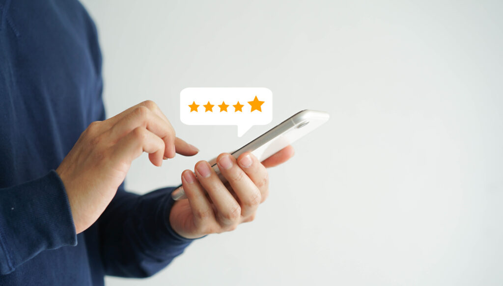 Male customer's hand pressing on smartphone screen with five-star rating